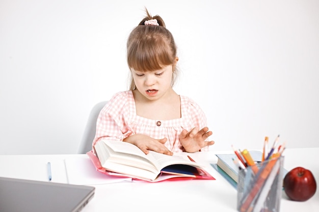 Foto gratuita chica con síndrome de down estudiando sentada en el escritorio en casa