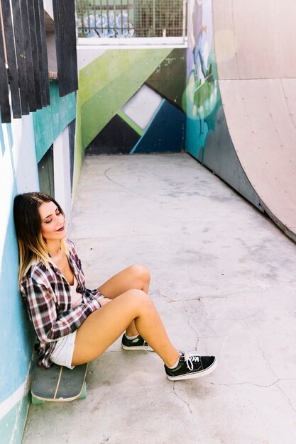 Chica skater joven sentada en tabla