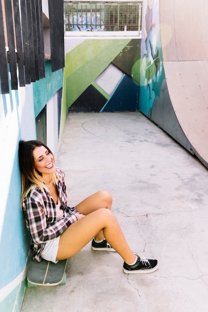 Chica skater sonriente sentada en tabla