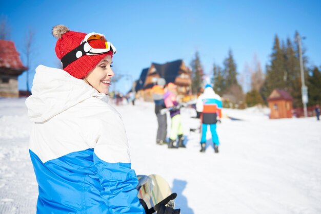 Chica de snowboard caminando por la ladera