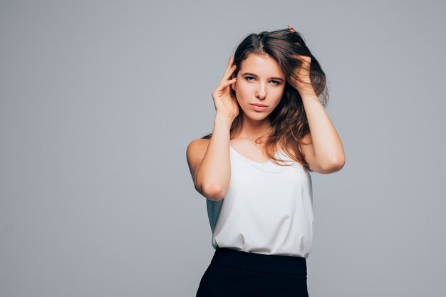 Chica soleada en vestido moderno de moda está posando en estudio sobre fondo blanco