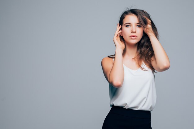 Chica soleada en vestido moderno de moda está posando en estudio sobre fondo blanco