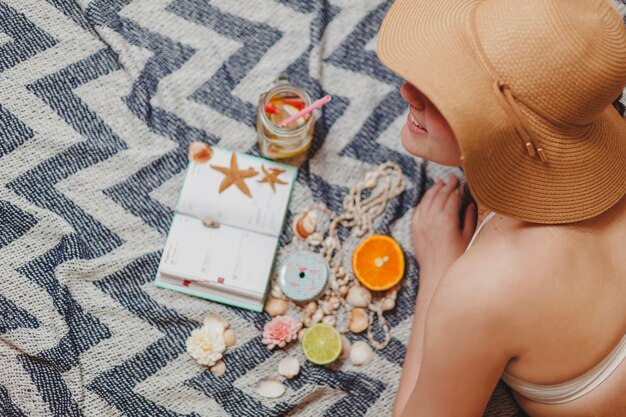 Chica con sombrero y agenda en la toalla de playa 