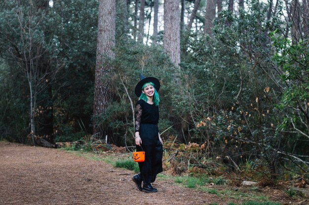 Chica en sombrero de bruja riendo en el bosque