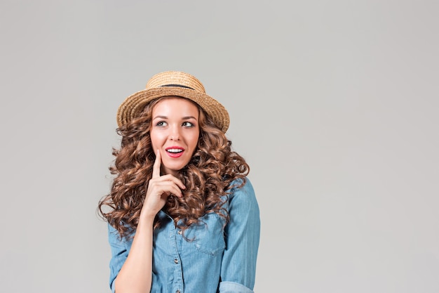 La chica con sombrero de paja en la pared gris del estudio