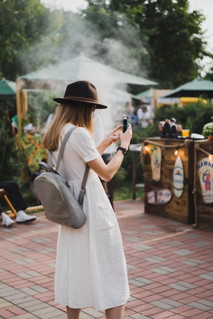 chica con sombrero toma un teléfono inteligente