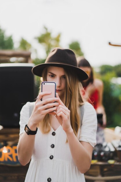 chica con sombrero toma un teléfono inteligente