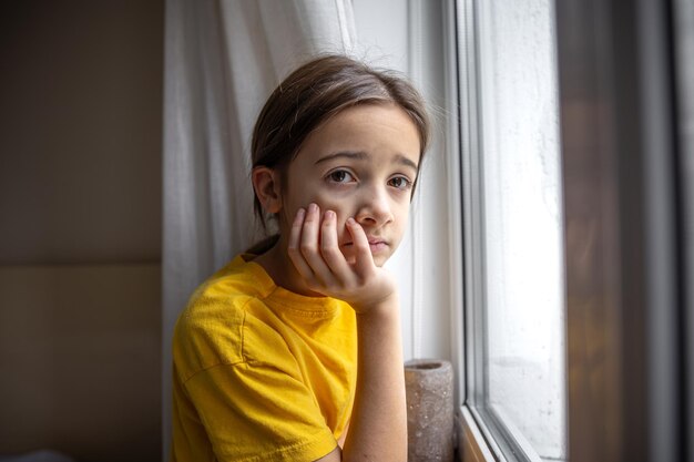 Una chica sombría y triste mira por la ventana concepto de emociones