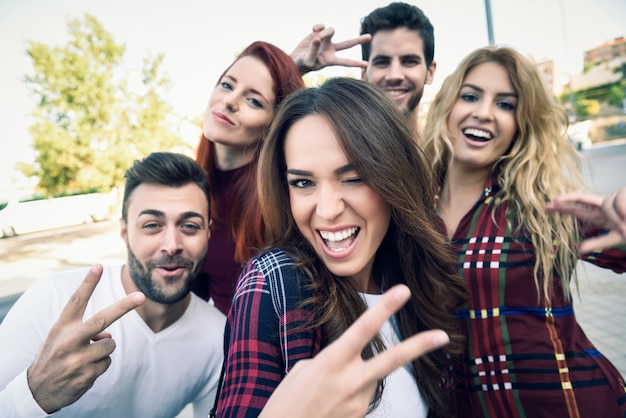 Chica sonriendo haciendo una autofoto con sus amigos alrededor