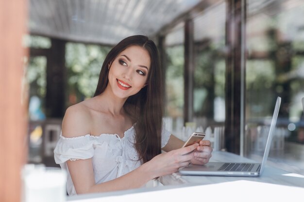 Chica sonriendo con un portátil en una cafetería