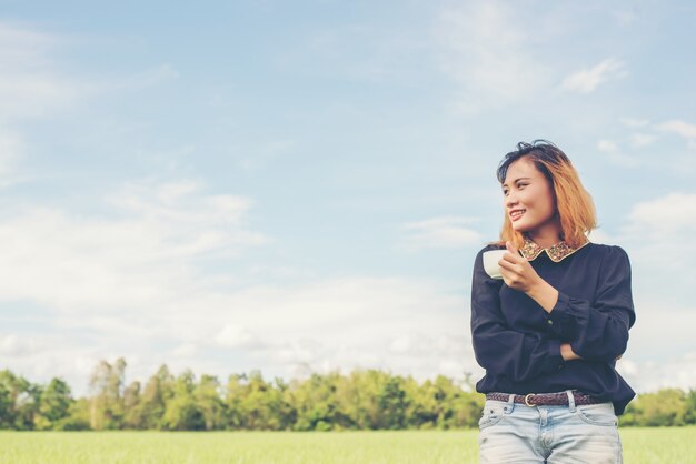 Chica sonriendo con una taza en el campo