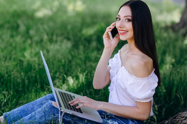 Chica sonriendo con un teléfono y un portátil