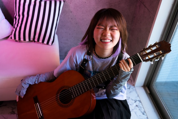 Chica sonriente de alto ángulo con guitarra