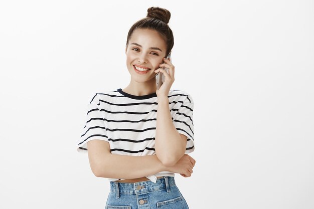 Chica sonriente atractiva alegre hablando por teléfono