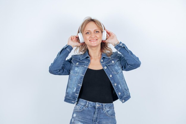 Chica sonriente con auriculares está mirando hacia arriba sobre fondo blanco.