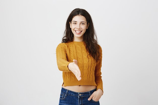 Chica sonriente confiada extiende la mano para apretón de manos. Joven profesional se presenta