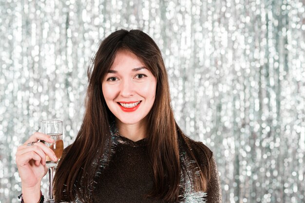 Chica sonriente con copa en fiesta de año nuevo