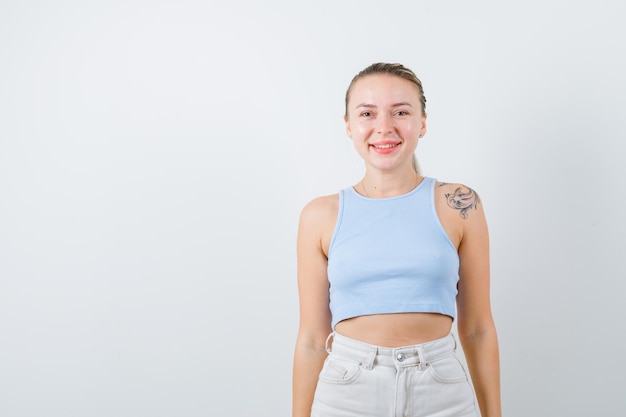 chica sonriente está posando en la cámara sobre fondo blanco