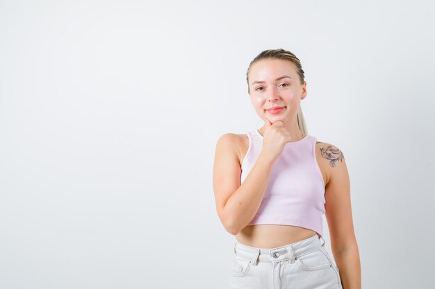 Chica sonriente está posando para la cámara sobre fondo blanco.