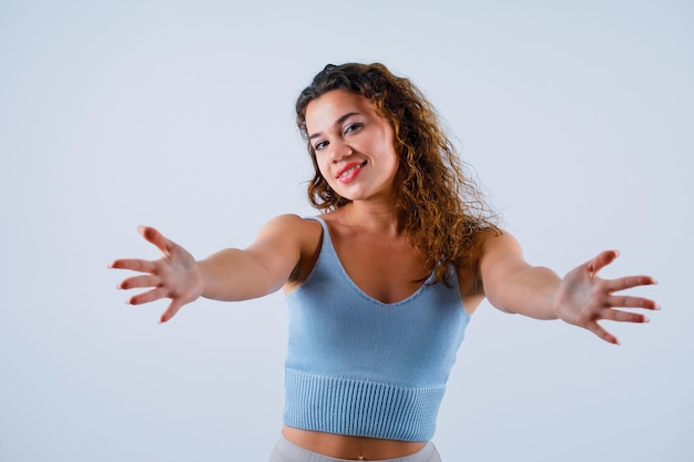 Foto gratuita chica sonriente está extendiendo las manos abriéndose a la cámara sobre fondo blanco.