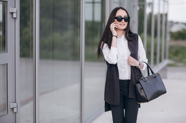 Chica sonriente con gafas de sol hablando por su teléfono