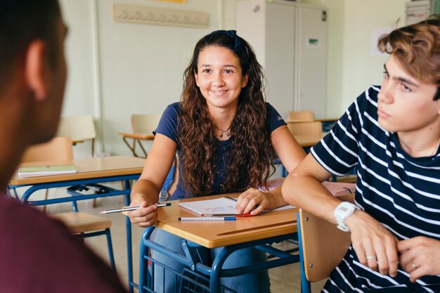 Chica sonriente hablando con los chicos en clase