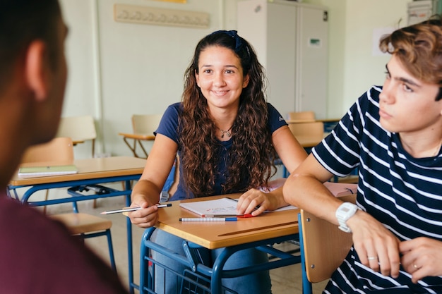 Chica sonriente hablando con los chicos en clase