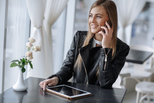 Chica sonriente hablando por teléfono sentada en un restaurante