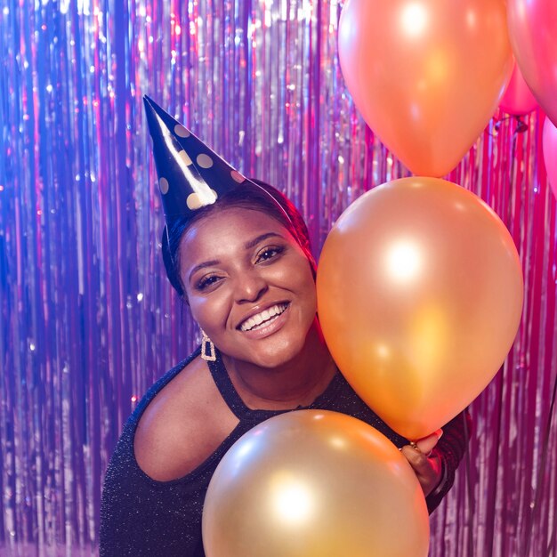 Chica sonriente sosteniendo globos tiro medio