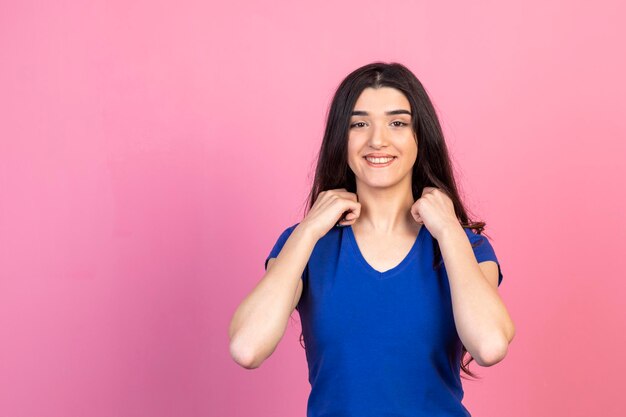 Chica sonriente sosteniendo sus manos en su cuello y sonriendo