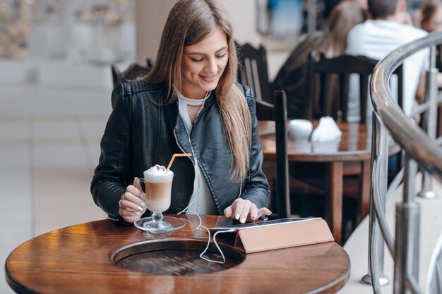 Chica sonriente con una tablet y un batido en una mesa