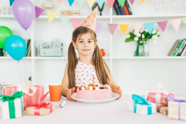 Chica sonriente con una tarta de cumpleaños