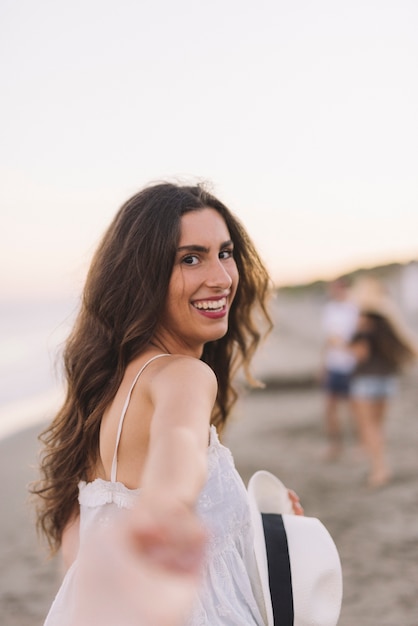 Foto gratuita chica sonriente tirando mano en la playa