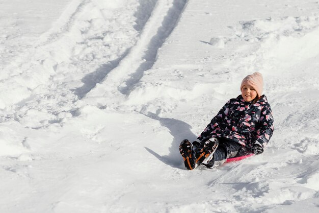 Chica sonriente de tiro completo en la nieve al aire libre