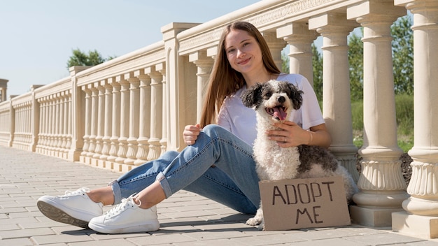 Foto gratuita chica sonriente de tiro completo sentada con lindo perro