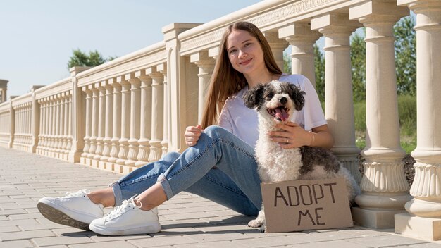 Chica sonriente de tiro completo sentada con lindo perro