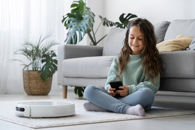 Foto gratuita chica sonriente de tiro completo con teléfono inteligente