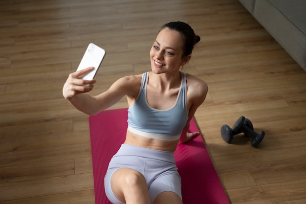 Chica sonriente tomando selfie ángulo alto