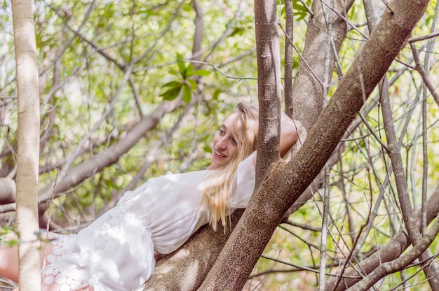 Foto gratuita chica sonriente tumbada en un árbol