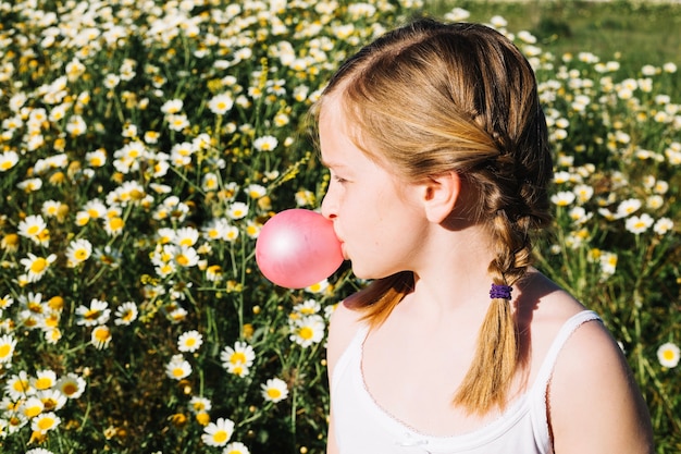 Foto gratuita chica soplando chicle en el campo de la manzanilla