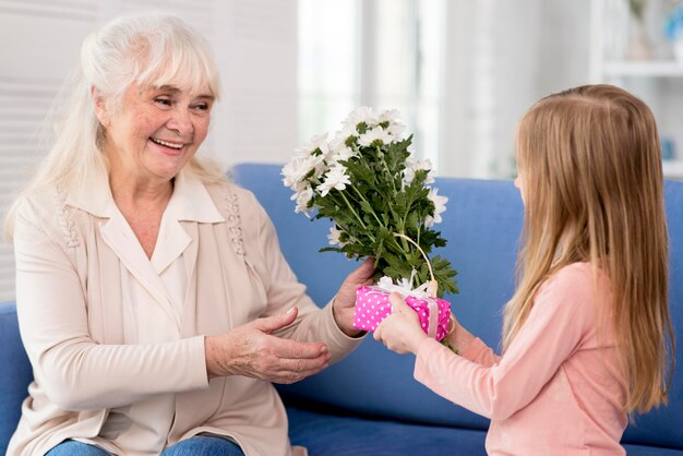 Chica sorprendente abuela con flores y regalo
