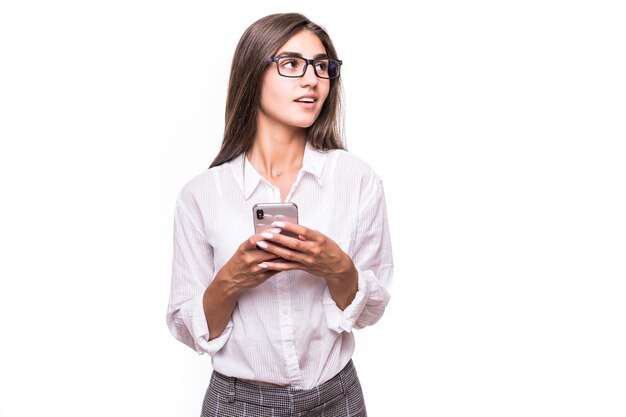 Chica sorprendida bastante feliz posando con teléfono móvil en la pared blanca