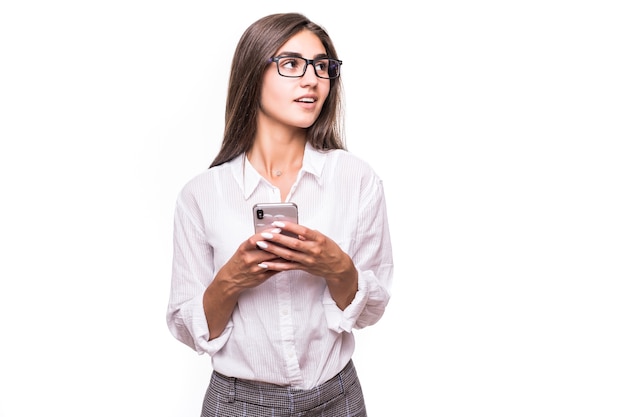 Chica sorprendida bastante feliz posando con teléfono móvil en la pared blanca