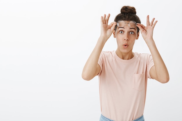 Foto gratuita chica sorprendida y emocionada con gafas posando contra la pared blanca