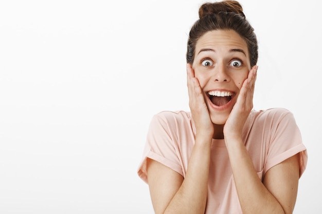 Foto gratuita chica sorprendida y feliz posando contra la pared blanca