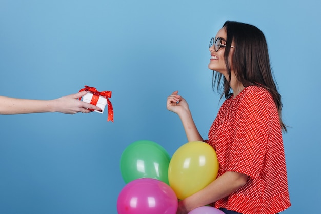 Foto gratuita chica sorprendida con gafas mira un pequeño regalo delante de ella