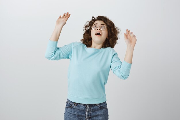 Chica sorprendida levantando las manos y mirando como algo cayendo sobre ella