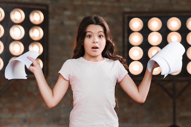 Chica sorprendida de pie delante de la luz de la etapa con scripts