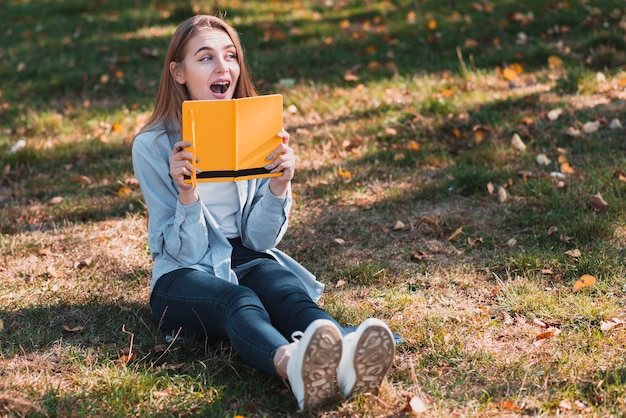Chica sorprendida sosteniendo un cuaderno amarillo
