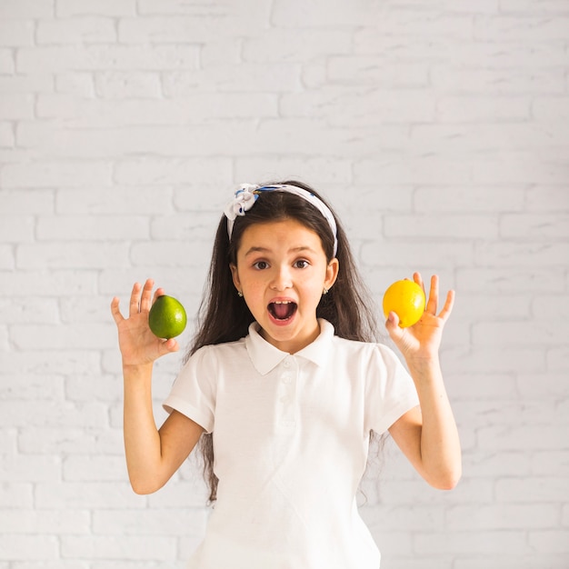 Chica sorprendida sosteniendo limón y limón en sus dos manos